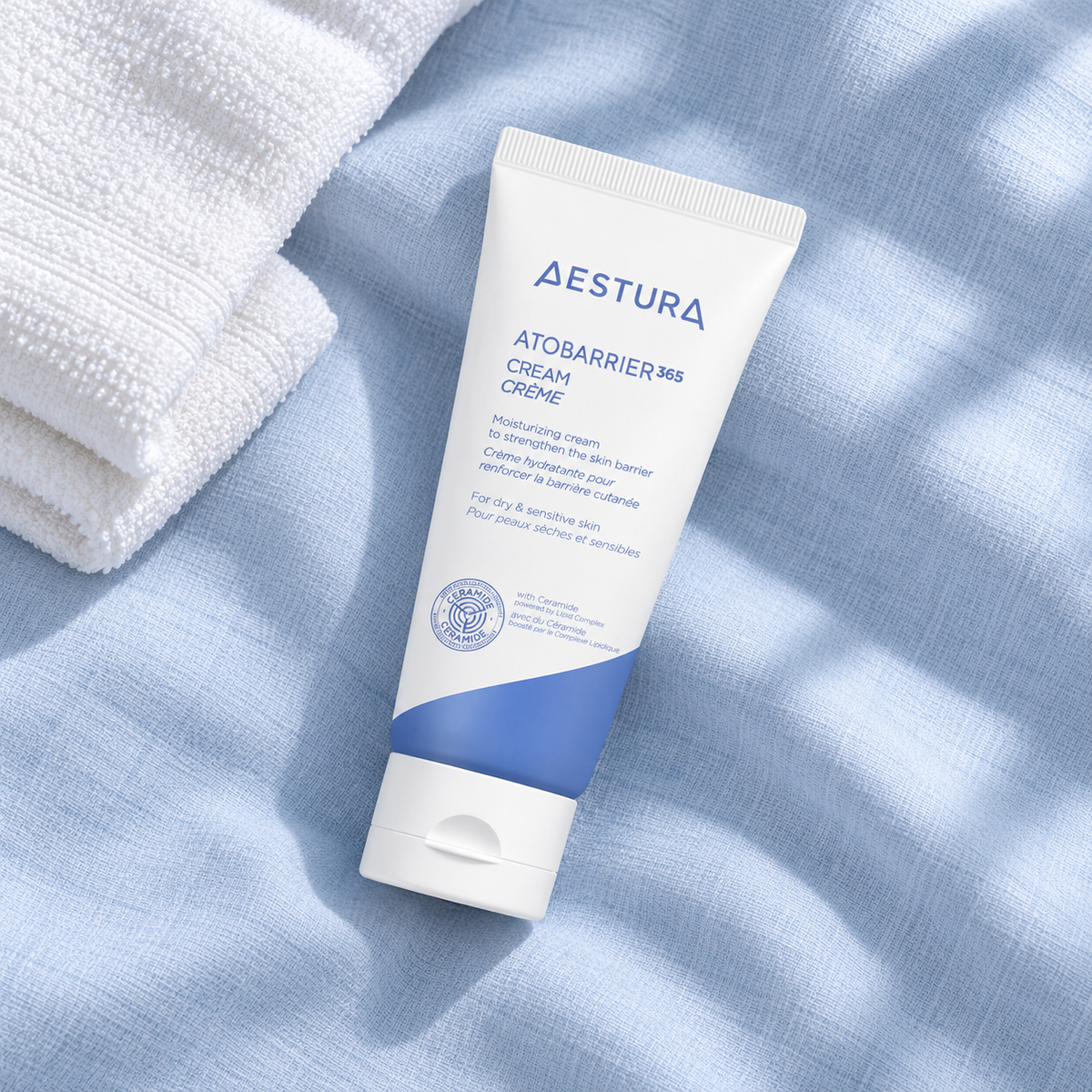 AI-styled flat lay of AESTURA ATOBARRIER365 Cream 80 ml on pale blue linen