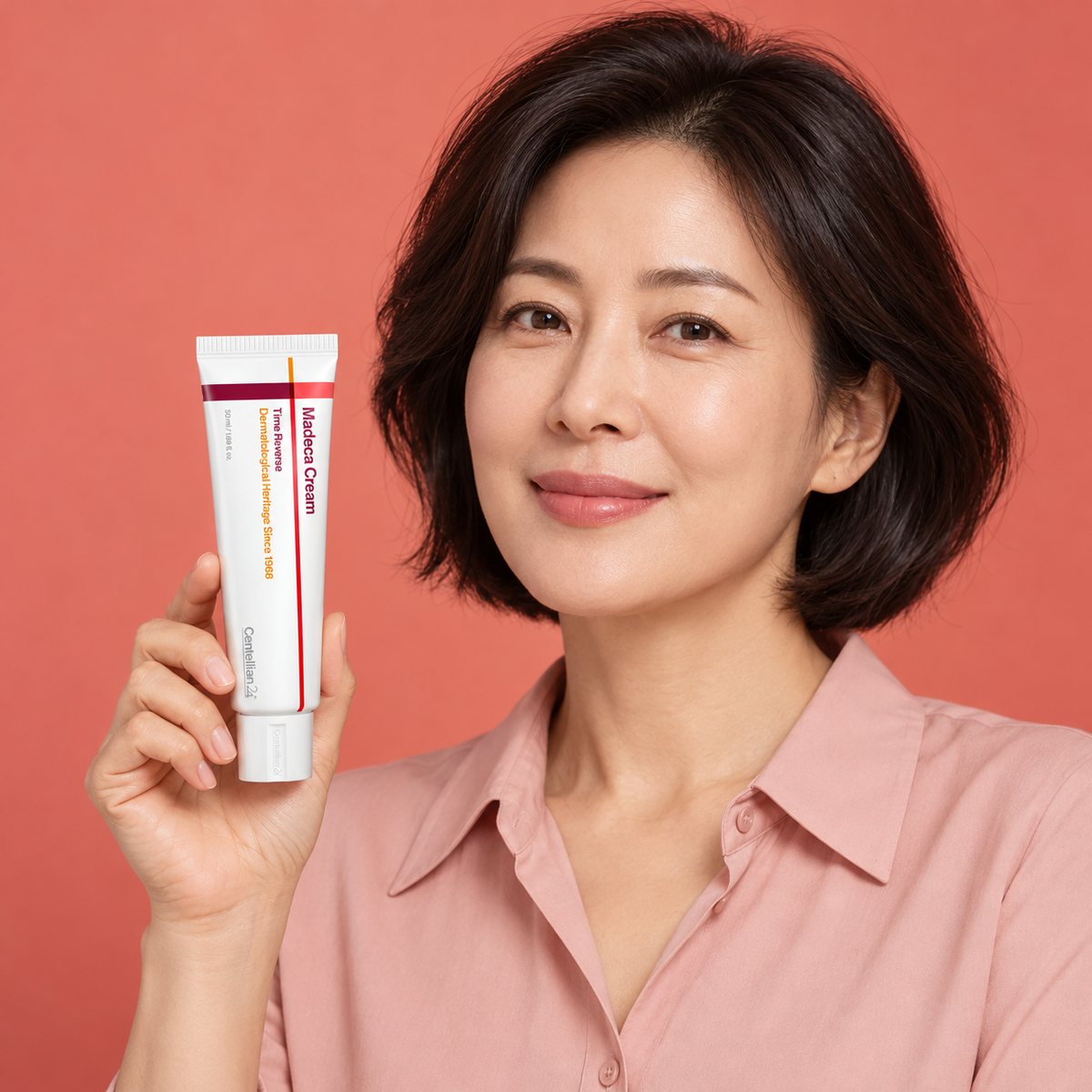Adult model holding a closed Centellian24 Madeca Cream Time Reverse tube against a coral background