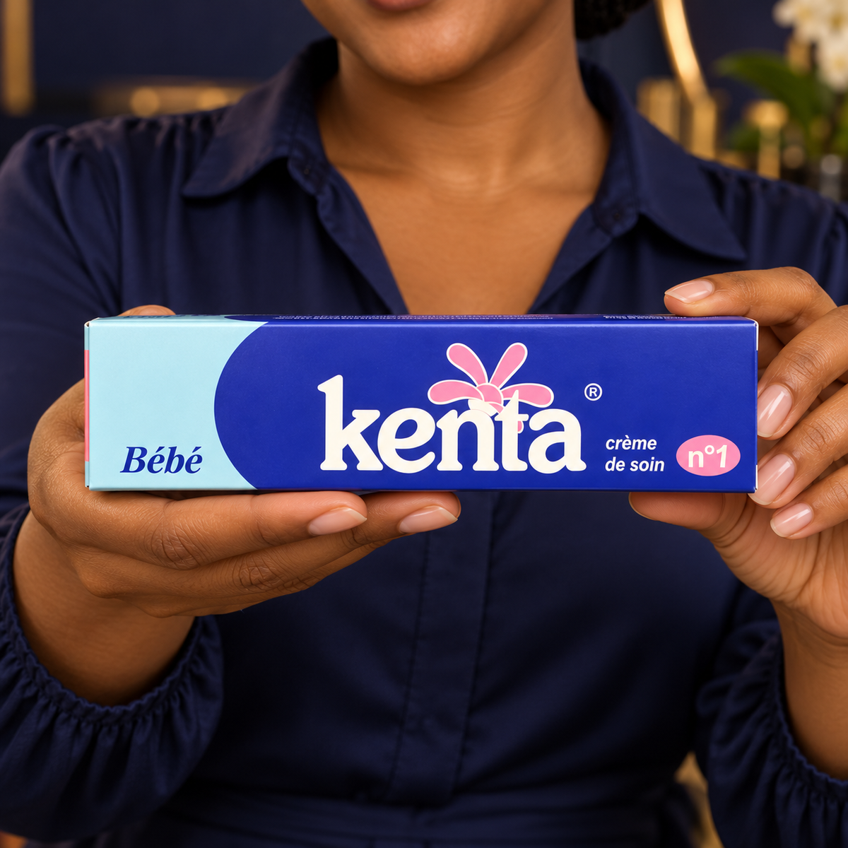 Close handheld front-label detail of the closed Kenta Bébé Crème de Soin n°1 carton, shown by the same adult woman