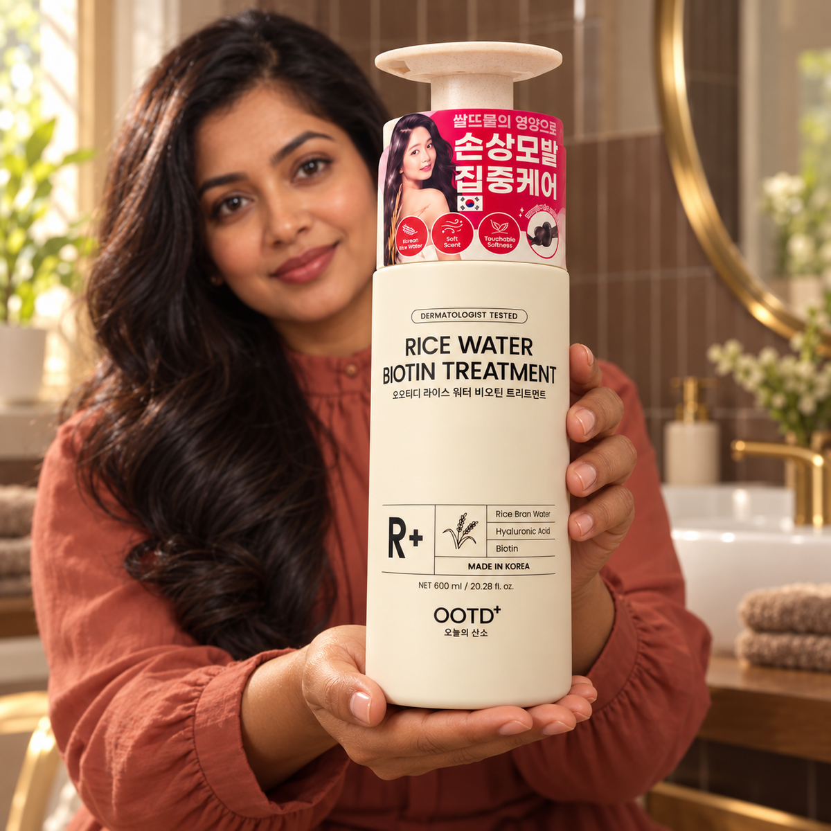OOTD+ Rice Water Biotin Treatment 600 mL bottle presented by a woman in a warm home bathroom
