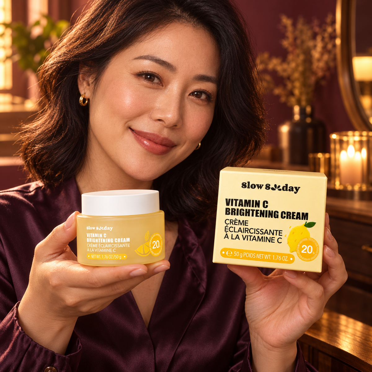 Woman actively presenting the Slow Sunday Vitamin C Brightening Cream 50 g closed yellow jar and retail carton in a richly colored setting
